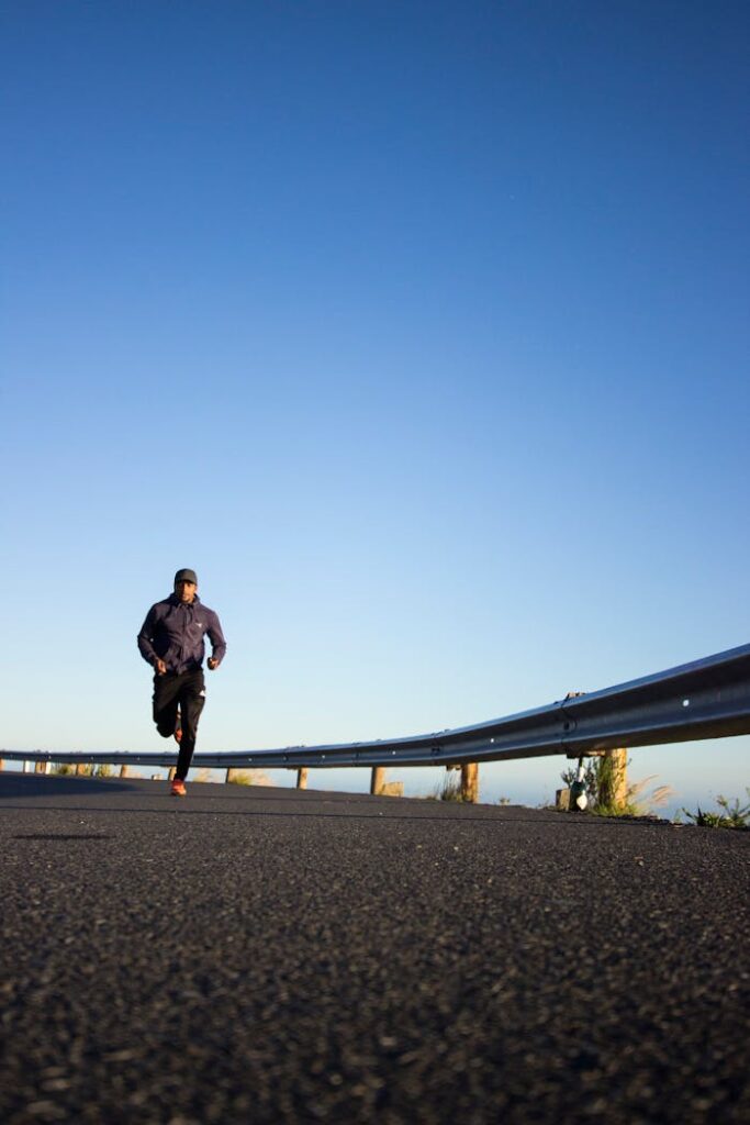 Current image: An athletic man jogging on an open road with a clear blue sky in Cape Town, South Africa.