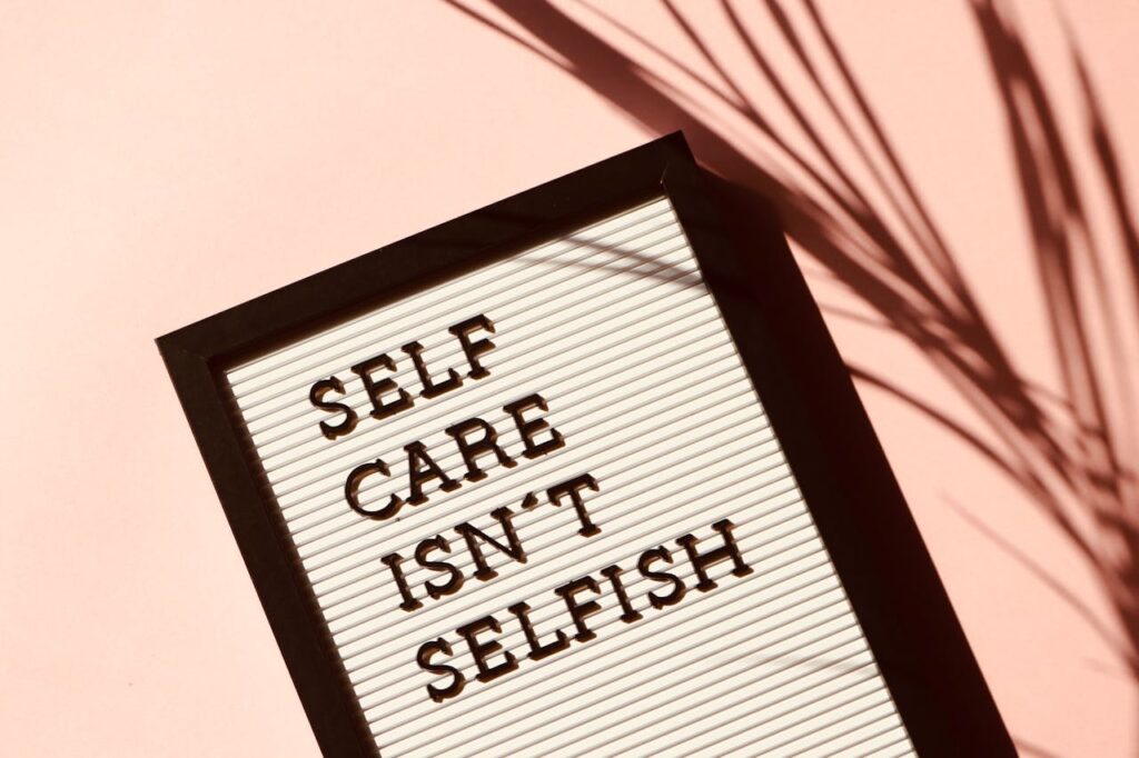 Current image: Letter board displaying 'Self Care Isn't Selfish' with artistic shadow on pink background.